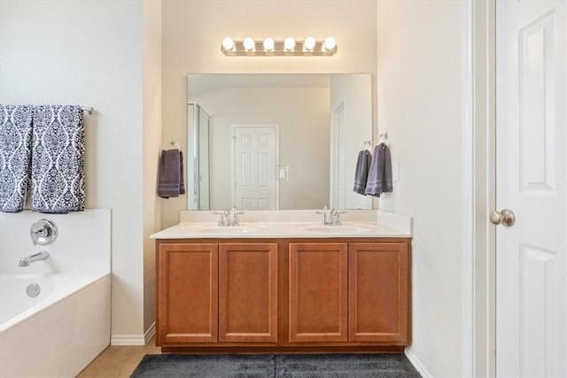 full bathroom with double vanity, a garden tub, baseboards, and a sink