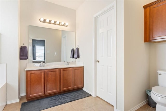 bathroom featuring toilet, double vanity, a sink, and tile patterned floors