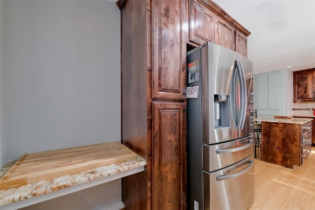 kitchen with wooden counters, backsplash, stainless steel fridge, and light hardwood / wood-style floors