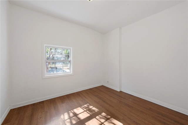 spare room with vaulted ceiling and hardwood / wood-style flooring