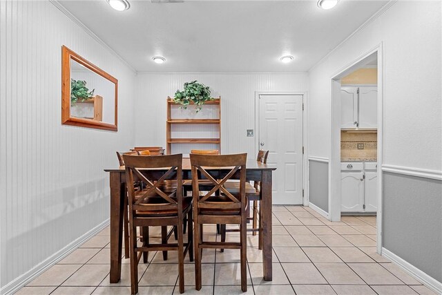 dining space with wood walls, light tile patterned flooring, and crown molding