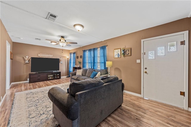 living area featuring a ceiling fan, light wood-type flooring, visible vents, and baseboards