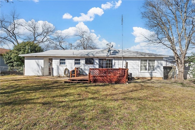 back of property with fence, a deck, and a lawn