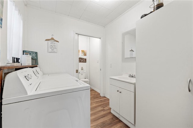 laundry room featuring light wood-style floors, laundry area, washer and clothes dryer, and a sink