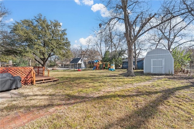 view of yard featuring a playground, an outdoor structure, a wooden deck, and a storage shed