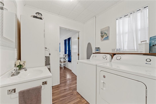 washroom with light wood-type flooring, crown molding, a sink, and independent washer and dryer