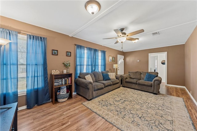 living area featuring light wood-style flooring, visible vents, baseboards, and ceiling fan