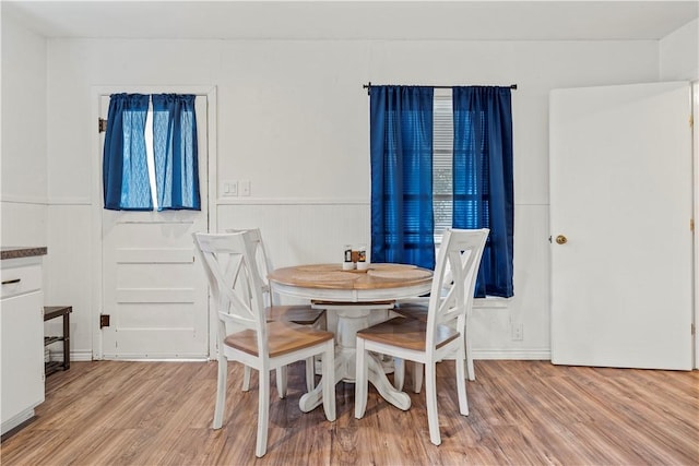 dining room featuring light wood-style floors and a wainscoted wall