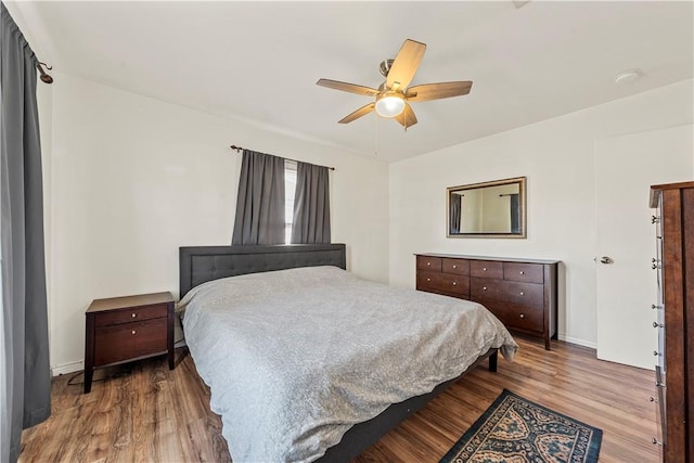 bedroom featuring wood finished floors, a ceiling fan, and baseboards