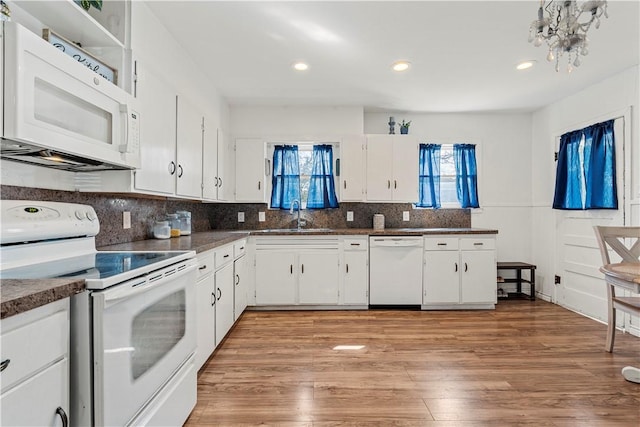 kitchen with dark countertops, white appliances, light wood-type flooring, and a sink