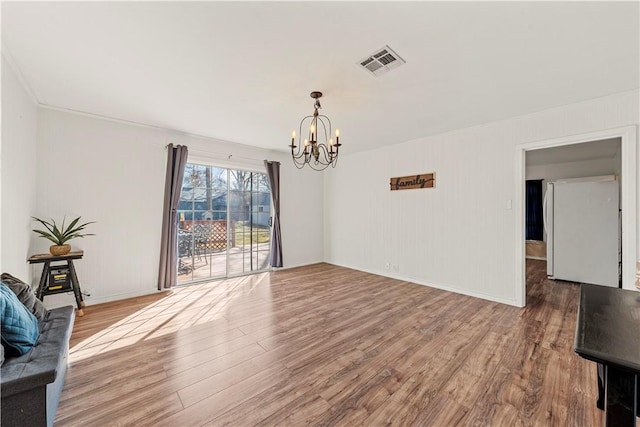 interior space with baseboards, a notable chandelier, visible vents, and wood finished floors