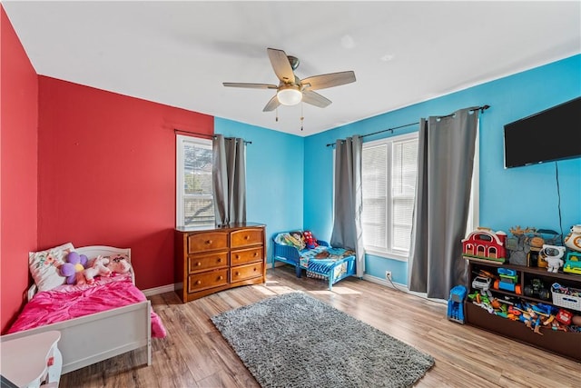 bedroom with multiple windows, ceiling fan, baseboards, and wood finished floors