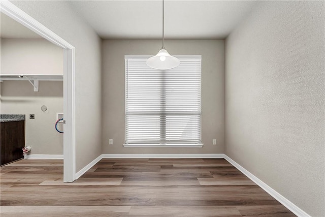 unfurnished dining area featuring baseboards and wood finished floors