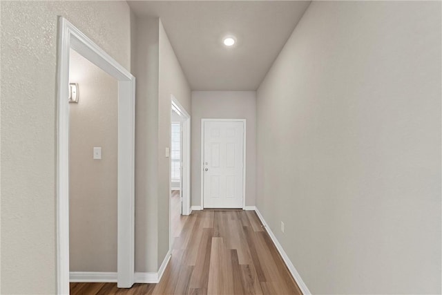 corridor featuring baseboards and wood finished floors