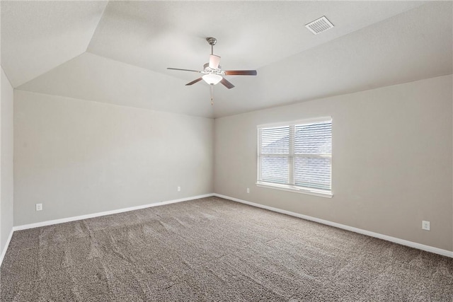 spare room with vaulted ceiling, carpet flooring, a ceiling fan, and visible vents