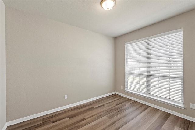 spare room with wood finished floors and baseboards