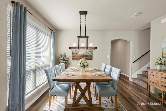 dining area with visible vents, wood finished floors, arched walkways, baseboards, and stairs