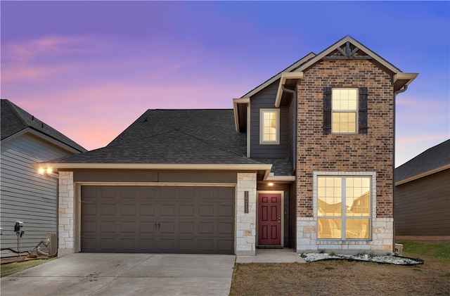 traditional-style home with stone siding, a garage, driveway, and roof with shingles