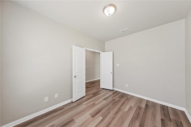 unfurnished room featuring baseboards, visible vents, and light wood-type flooring