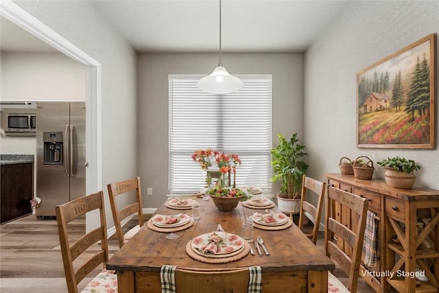 dining area featuring baseboards and light wood-style flooring