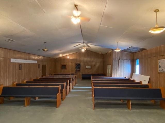 misc room featuring wood walls, ceiling fan, and vaulted ceiling