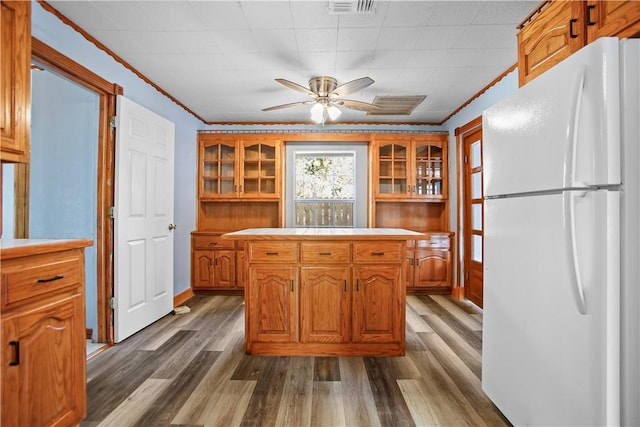 kitchen featuring ornamental molding, ceiling fan, hardwood / wood-style floors, white fridge, and a kitchen island