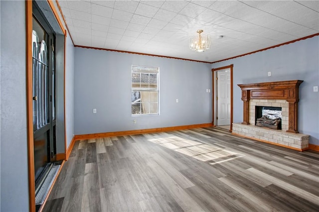 unfurnished living room featuring crown molding, a chandelier, a fireplace, and hardwood / wood-style floors