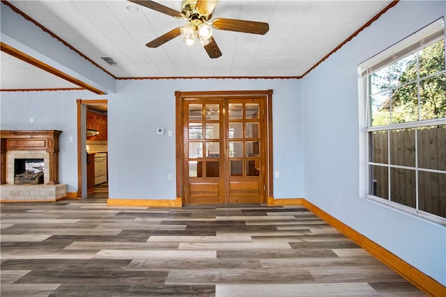 interior space featuring a tile fireplace, crown molding, ceiling fan, and hardwood / wood-style flooring