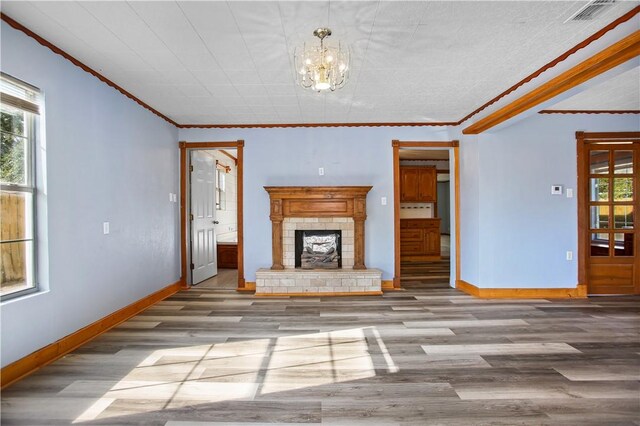 unfurnished living room featuring a fireplace, an inviting chandelier, light wood-type flooring, and ornamental molding