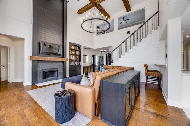 living area with built in features, a large fireplace, stairway, and hardwood / wood-style flooring