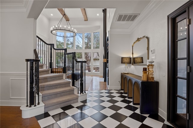 entryway featuring visible vents, crown molding, a decorative wall, and beamed ceiling