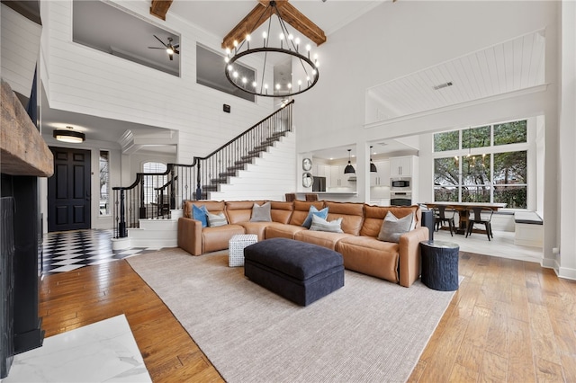 living area with stairs, a high ceiling, wood-type flooring, and crown molding