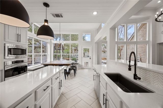 kitchen with stainless steel appliances, visible vents, a sink, and an inviting chandelier