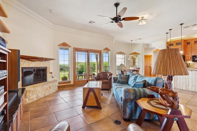 tiled living room featuring crown molding, a fireplace, and ceiling fan