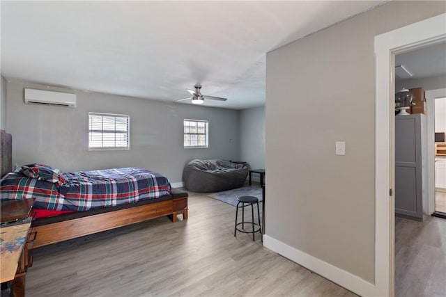 bedroom with light hardwood / wood-style flooring, an AC wall unit, and ceiling fan