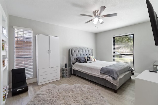 bedroom featuring ceiling fan, light hardwood / wood-style floors, a closet, and multiple windows