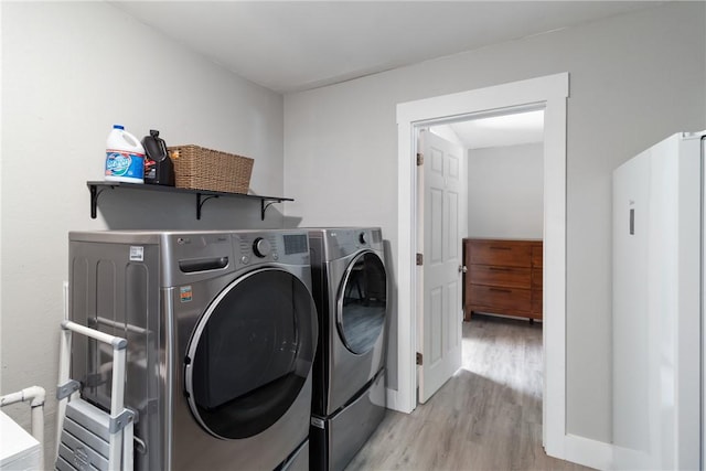 laundry area with washer and clothes dryer and light hardwood / wood-style floors