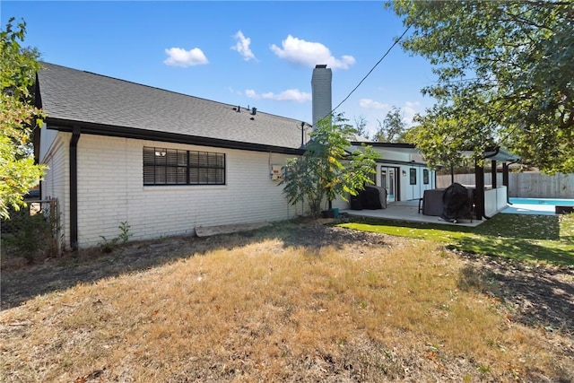 rear view of property with a patio and a lawn