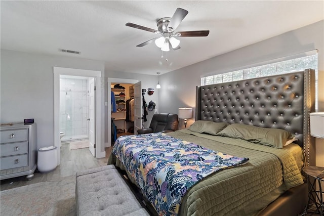 bedroom featuring ensuite bathroom, a walk in closet, light hardwood / wood-style flooring, ceiling fan, and a closet