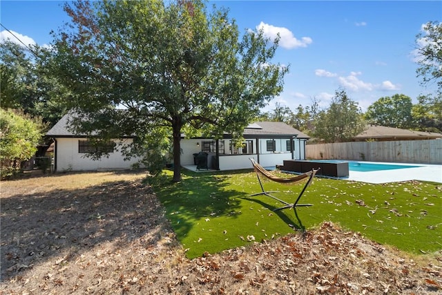 rear view of house with a swimming pool with hot tub, a yard, and a patio area