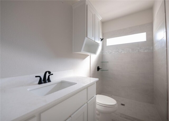 bathroom featuring a tile shower, vanity, toilet, and wood-type flooring