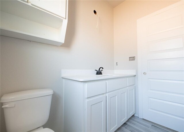 bathroom with hardwood / wood-style floors, vanity, and toilet