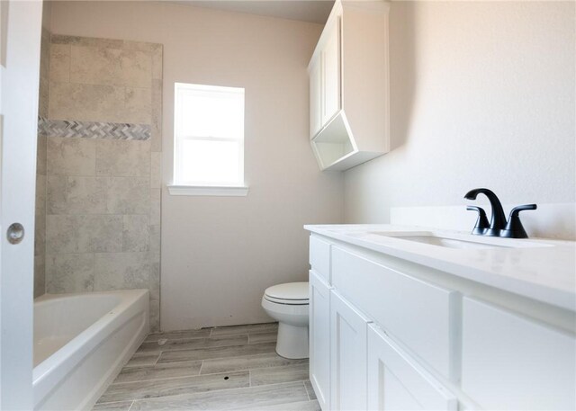 full bathroom with hardwood / wood-style floors, vanity, toilet, and tiled shower / bath