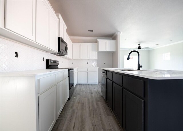 kitchen with black appliances, a center island with sink, white cabinetry, and sink