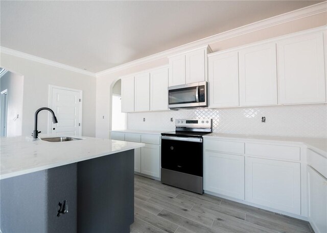 kitchen featuring sink, stainless steel appliances, light stone counters, white cabinets, and ornamental molding