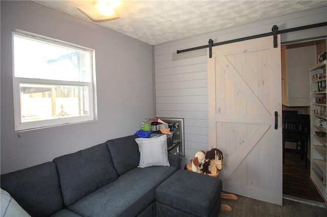 living room featuring dark hardwood / wood-style flooring, a barn door, a textured ceiling, and wood walls