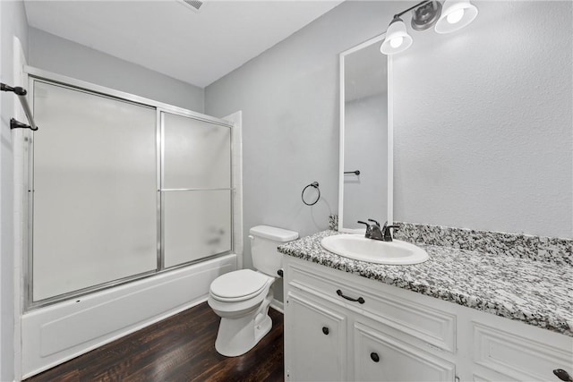 full bathroom with enclosed tub / shower combo, wood-type flooring, vanity, and toilet