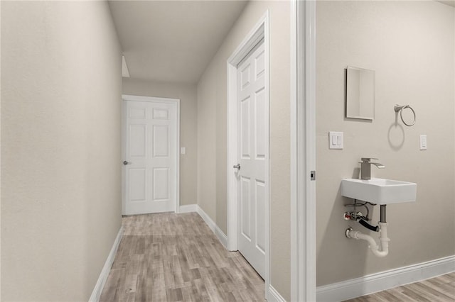 corridor featuring sink and light hardwood / wood-style floors