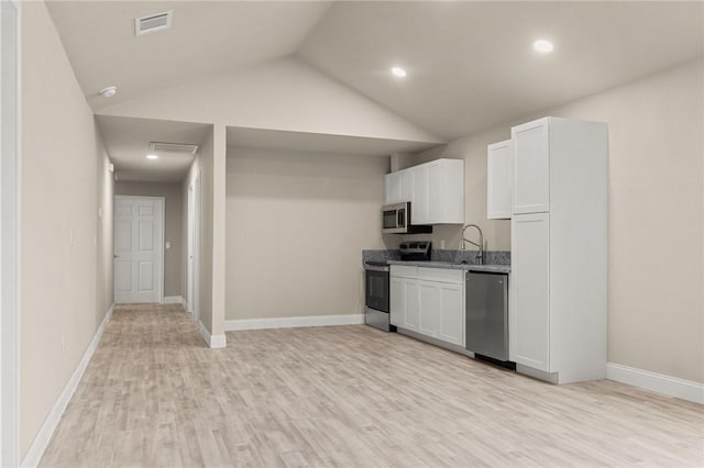 kitchen with light stone countertops, light wood-type flooring, stainless steel appliances, white cabinetry, and lofted ceiling