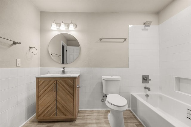 full bathroom featuring shower / bathing tub combination, vanity, toilet, and tile walls